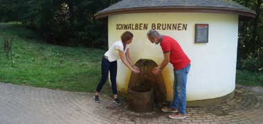 Spaziergänger erfrischen sich am Schwalbenbrunnen