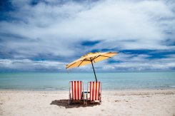 Beach parasol and red beach chairs on a shore Beach parasol and red beach chairs on a shore