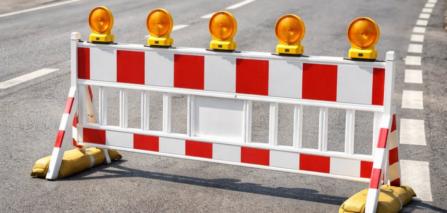 Eine rot-weiße Barriere steht auf einer STraße